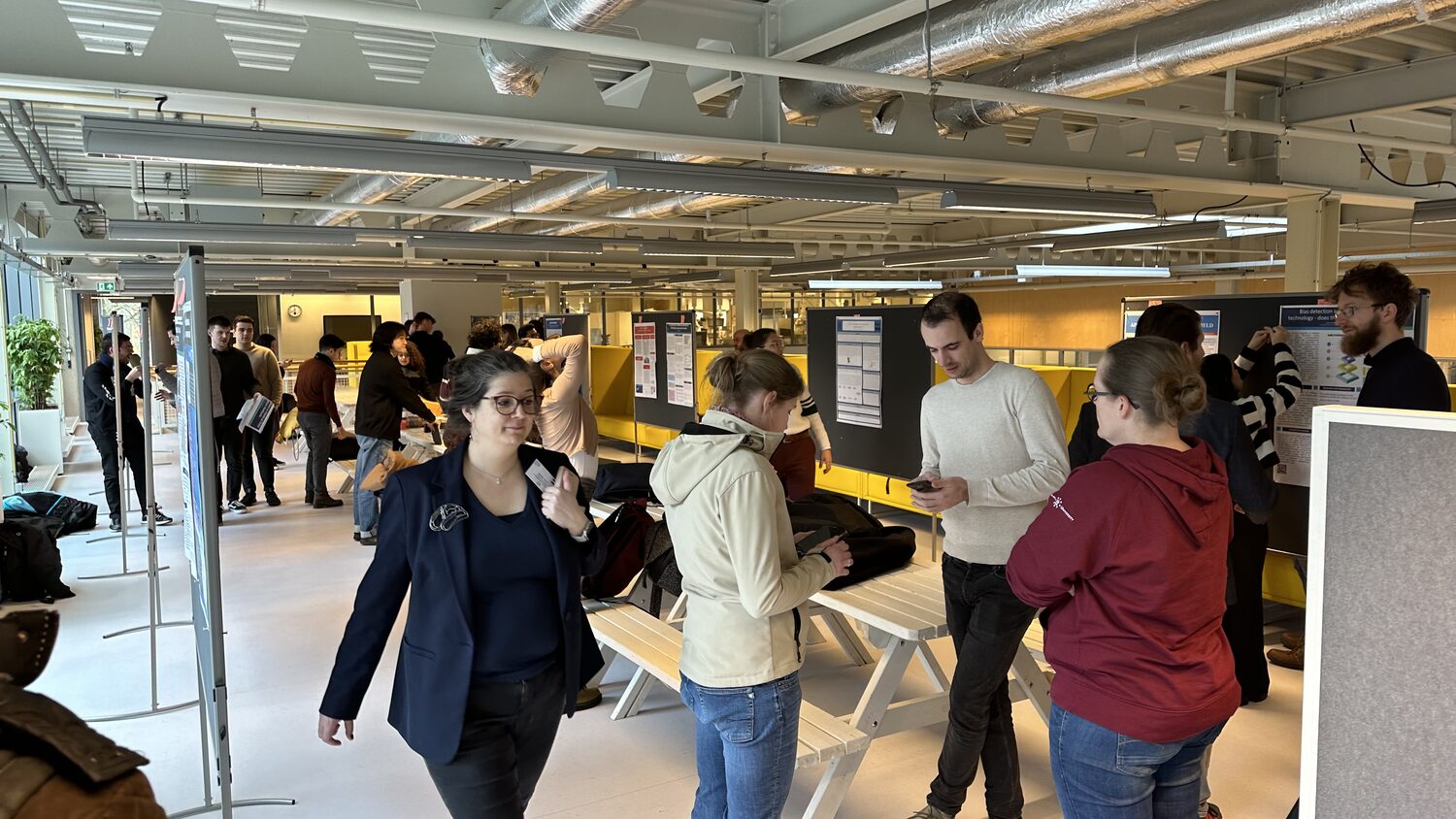 Students and staff talk beside poster boards and long benches on the poster floor, 2 February 2024.