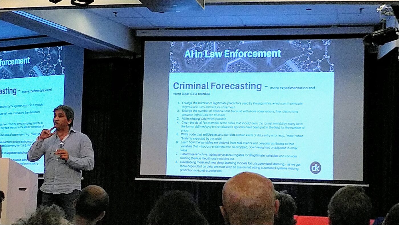 Tarry Singh works through the slide headed AI in Law Enforcement, Criminal Forecasting, with the heads of the front rows of the audience in the foreground.