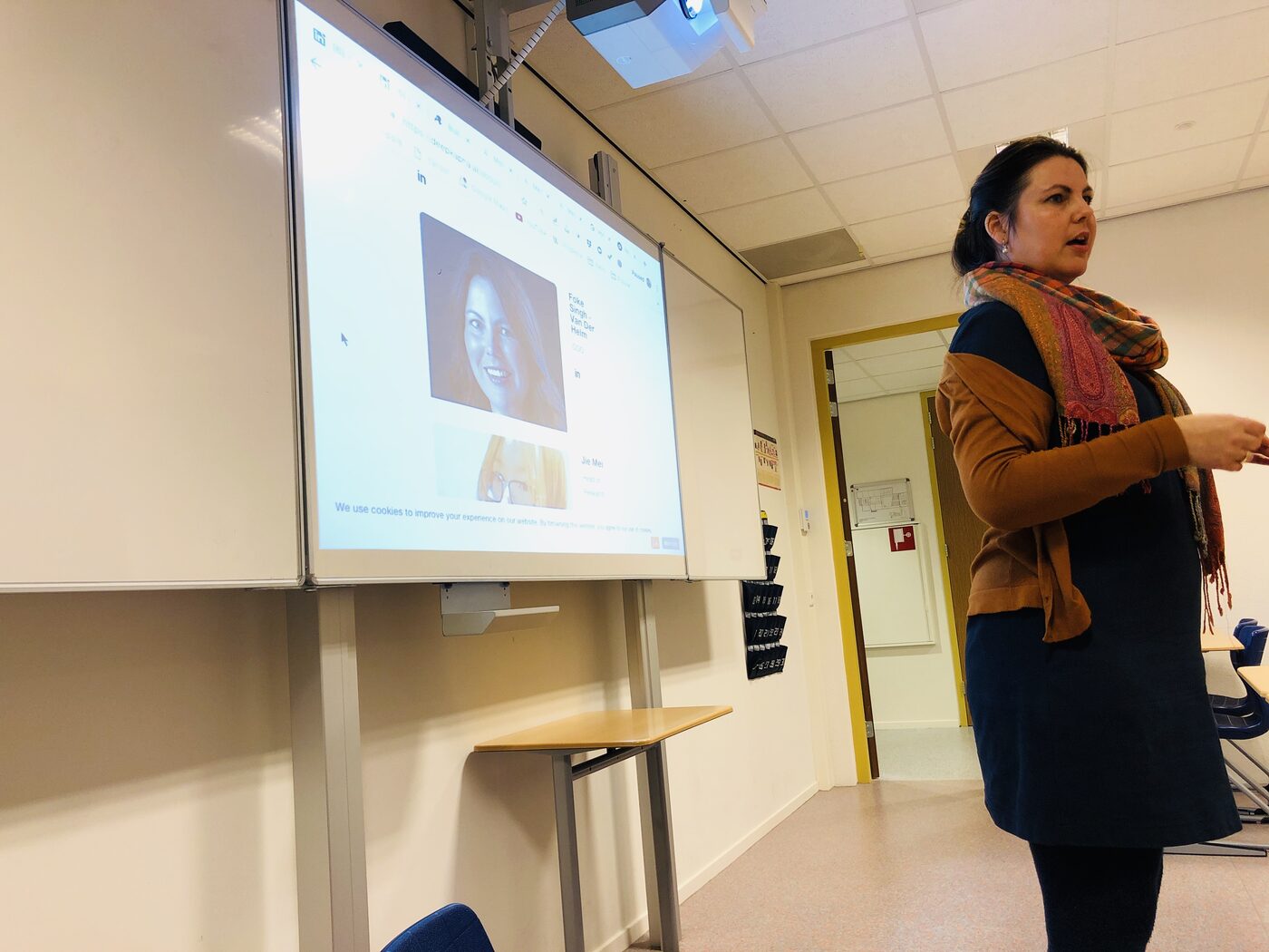 The speaker gestures towards the projected deepkapha.ai team page, which carries her own entry and that of Jie Mei, head of research.